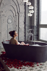 sexy beautiful woman lies in stone bath with foam