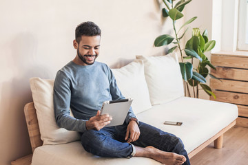 Handsome young man using digital tablet at home. Student men resting t in his room. Home work or...