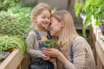 Obraz premium A young woman with a small daughter is planting a plant in a pot.
