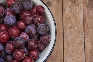 Plum in a bowl on a wood table. Agriculture, Gardening, Harvest Concept.