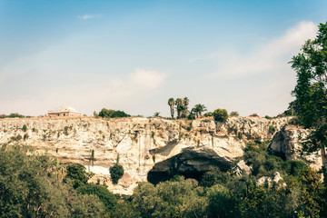 Fototapeta na wymiar Archeological park, rocks near Greek Theatre of Syracuse, ruins of ancient monument, Sicily, Italy.