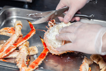 Cook chef is carving fresh red big boiled prepared blue kamchatka crab with scissors. Concept useful seafood in a menu, chef of premium restaurant preparing crab for serving for guests, clients