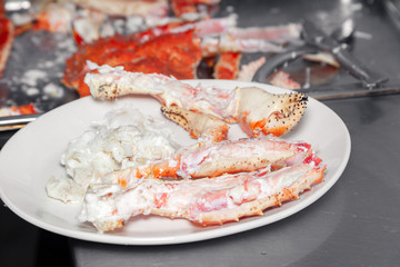 Closeup round white dish with fresh red big boiled prepared blue kamchatka crab. Concept useful seafood in a menu premium restaurant preparing, serving for guests, clients