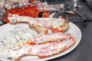 Closeup round white dish with fresh red big boiled prepared blue kamchatka crab. Concept useful seafood in a menu premium restaurant preparing, serving for guests, clients