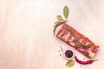 Raw pork loin with species and herbs. Large piece of pickled (marinated) meat on a stone background, top view