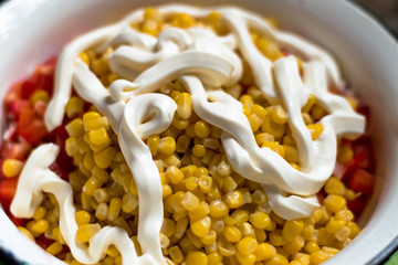 Fresh salad of corn, red pepper, crab sticks, potatoes and mayonnaise on top