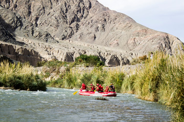 A group of young people practice and enjoy a beautiful day to go rafting. River, landscape, friends and extreme sports are the perfect combination for a unique day.