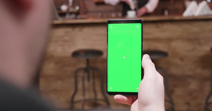 Handheld Of Holding A Phone With Green Screen And Looking At It