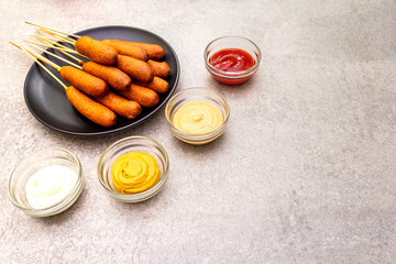 Corn dogs homemade with popular sauces. Traditional American street food. On stone background