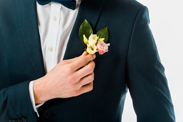 cropped view of bridegroom in black costume jacket with boutonniere isolated on white