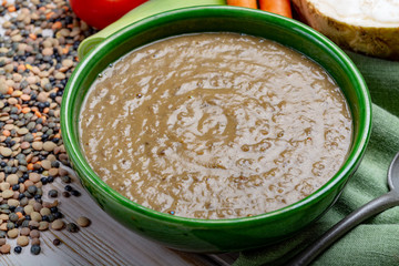 Tasty vegetarian food, green bowl with lentils soup with vegetables, good for vegans
