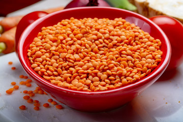 Dried orange lentils legume in red bowl