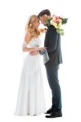 beautiful bride in white wedding dress, and groom in elegant black suit standing face to face...