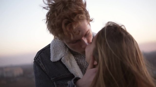 Young couple kissing on sky cityscape background, youth love, togetherness. Romantic date on the high roof