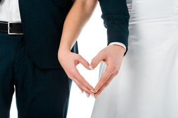 cropped view of bride and groom showing heart sign with hands isolated on white