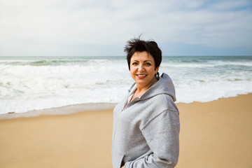 Portrait of a Happy mature woman walking on the Ocean Beach. Enjoying Freedom of Travel Vacation. Wellness and Happiness Lifestyle Concept. Portugal. Santa Cruz