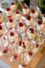 details from a wedding dessert table - vanilla cream with fresh red raspberries in fancy glasses with spoons