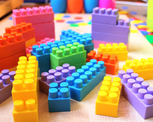 Obraz premium Children's color blocks on a light wooden floor on the background of toys.