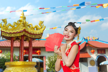 A beautiful asian girl wearing a red dress holding paper fan in her hand and smiling makes her look happy.