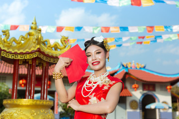A beautiful asian girl wearing a red dress holding paper fan in her hand and smiling makes her look happy.