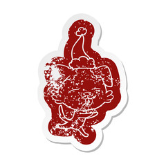cartoon distressed sticker of a dog sticking out tongue wearing santa hat