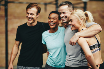 Laughing group of diverse friends standing together in a gym