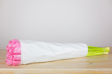 Gently pink tulips in white wrapping paper close-up. The concept of selling flowers