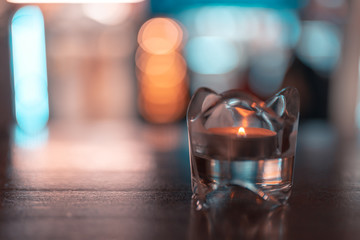 glass of water and burning candles on black background