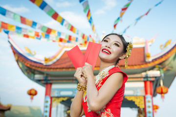 Obraz premium A beautiful asian girl wearing a red dress holding paper fan in her hand and smiling makes her look happy.