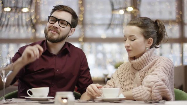 Adult businessman using smartphone payment in a restaurant sitting in a restaurant by table with his girlfriend