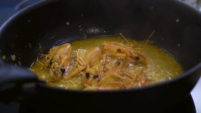 Cooking prawns' head in a pan with wine and onion, prawns jus