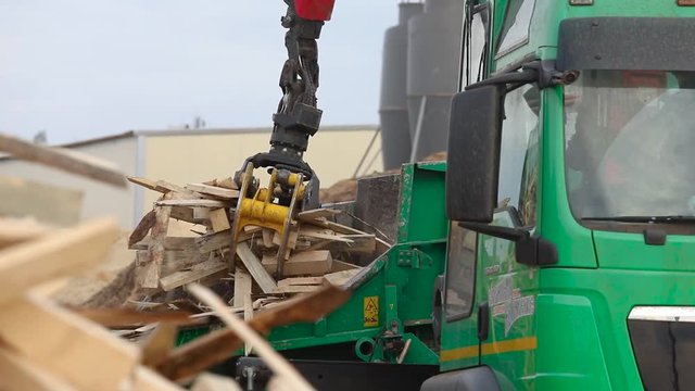 Machine with a manipulator. The manipulator loads firewood in a shredder for firewood. Biofuel production