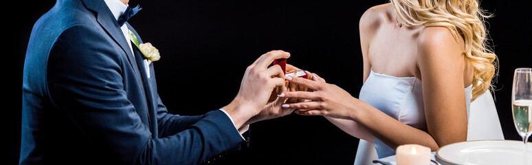 panoramic shot of man making marriage proposal to woman isolated on black