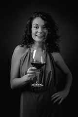 Portrait of attractive brunette in long evening dress with glass of red wine.