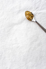 Dried herbal teas on vintage metal silver spoons on white fabric table top background with empty copy space. Organic healthy lifestyle and well-being concept. Vintage food and drink setting styling. 