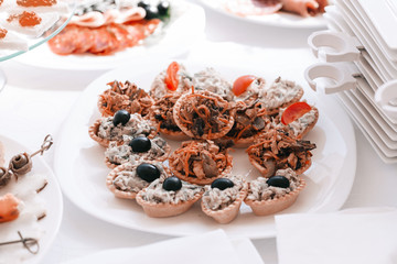 slices of salmon, rolls of pancakes and mushrooms on a snack plate