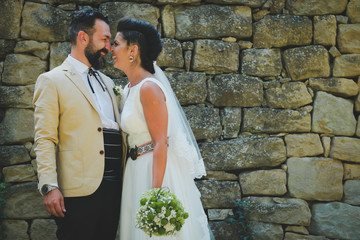 bride and groom kissing in front of stone wall