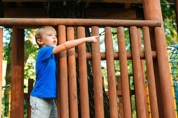 Obraz premium Cute kid playing in tree house on backyard. Happy childhood. Summer holidays concept. Tree house for kids. Happy boy plays in an adventure park.