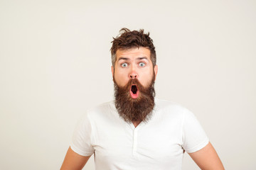 Shocked bearded man stares at camera. Bearded hipster guy widely opened mouth and eyes. Human face expressions and emotions. Wow! Surprised young man on white background