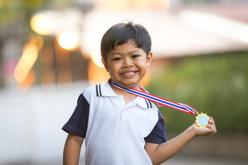 A 5 years old boy showing his golden medal.