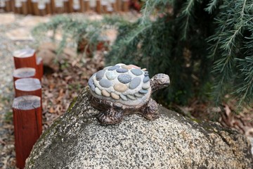 Turtle ornament on granite rock in garden