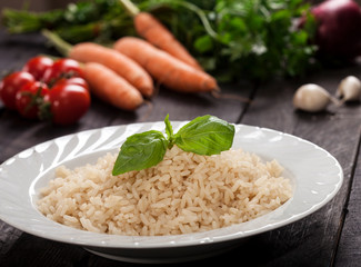 Cooked white rice in a plate on black wooden background.