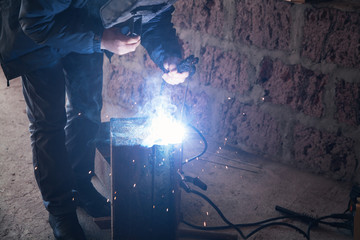 Welder performs welding work on metal in protective mask.