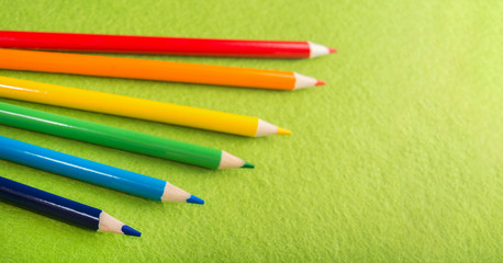 Six multicolored pencils on a green felt background. Different colored pencils with space for text. Back to school. Art lessons. Stationery.