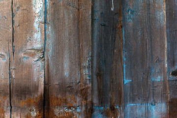 Old wooden planks. Blue and brown dry wood. Planks painted in blue paint. Peeling paint. Cracks. Natural Texture.