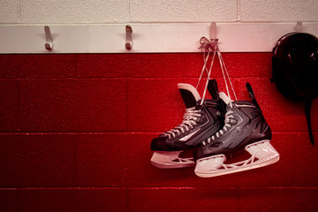 Hockey skates and helmet hanging in locker room with red gradient background and copy space