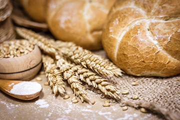 Freshly baked bread, wheat and flour on a rustic background