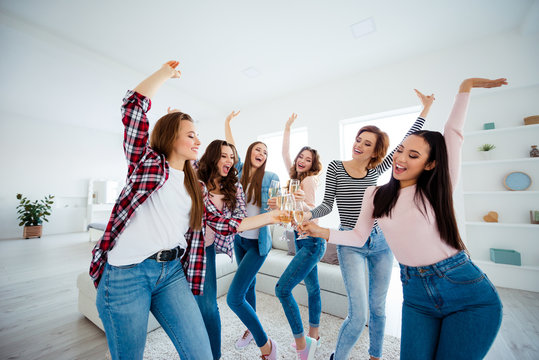 Nice graceful charming attractive cheerful cheery positive ladies clinking wine raising hands up cool vacation in modern light white interior room indoors