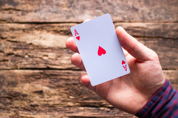 card player holds aces on a wooden background with space for text