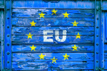 Old, poorly painted and partially peeled blue wooden surface with symbols of the European Union